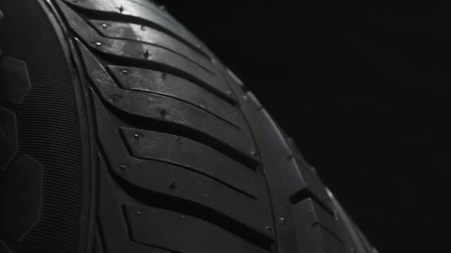 Tire Slowly Rotates on a Black Background. The car wheel slowly rotates in front of the camera, which is located at the lowest point, under the wheel