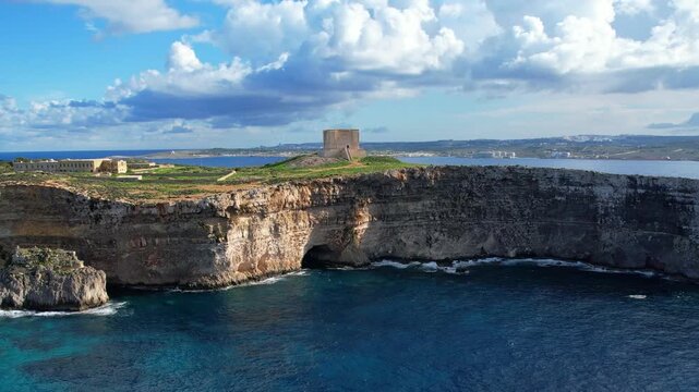 Aerial view of mesmerizing turquoise crystal clear blue water at Blue Lagoon with surrounding cliffs and caves and lush greens on Comino Island Malta on a warm sunny day in summer