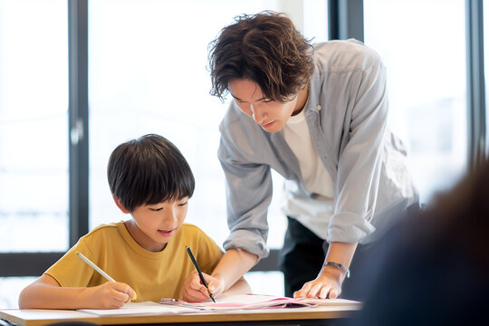 個別指導塾で男性講師から熱心に教わりながらノートをとる小学生の男の子の風景