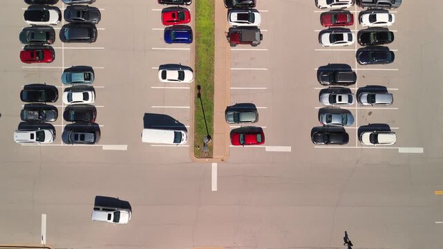 Top down aerial view of organized parking lot with parallel rows and central median on a sunny day