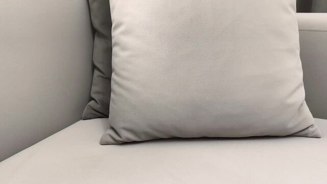 Smartphone with green screen stands against pillow on sofa and hand picks it up. Device with chroma display rests on cushion at home. Concept app mockup, mobile usage, digital interaction..