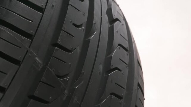 Tire Slowly Spinning on White Background. The car wheel slowly rotates in front of the camera, which is located at the lowest point, under the wheel. Smoke billows on a white background