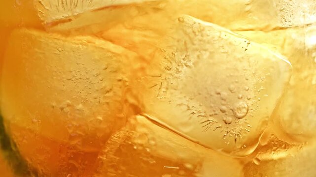 Refreshing macro shot of fresh lemon slice falling into ice cold golden amber iced tea cocktail or whiskey with ice cubes summer drink 