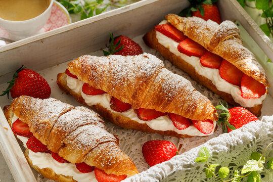 Croissants with strawberries and whipped cream, close-up. A delicious dessert or breakfast.