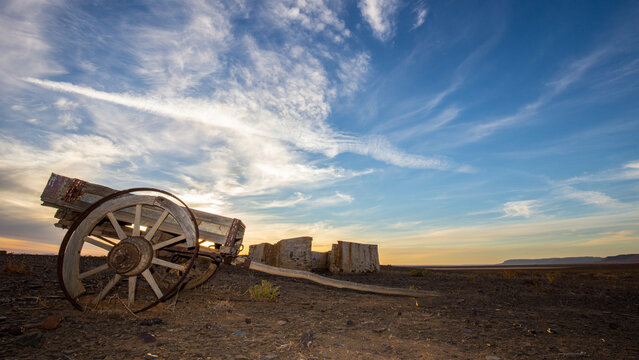 Old ox wagon near abandoned dwelling in the Tankwa Karoo National Park at sunset with clouds in the sky