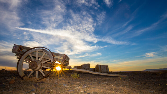 Old ox wagon near abandoned dwelling in the Tankwa Karoo National Park at sunset with clouds in the sky