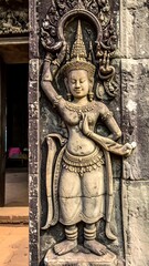 Fototapeta premium Stone carving of a celestial female figure, arms raised, adorned in ornate jewelry. The figure is framed by an arched design