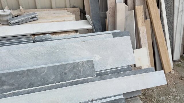 Gray marble slabs stacked outdoors, showcasing texture and pattern for construction materials