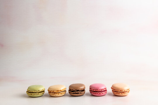 Macaroons lined up in a row on a light surface 