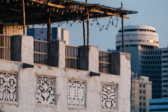Traditional Arabian architecture with ornate plasterwork contrasts with modern buildings in Dubai's historic district.
