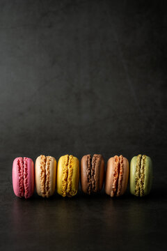 Stack of multi colored and flavored macaroons on a dark surface 