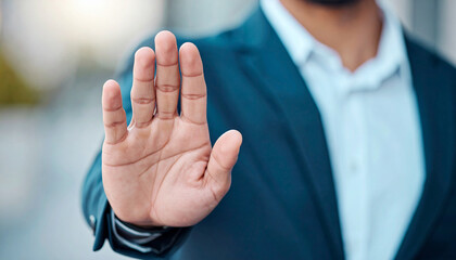 Obraz premium Hand of businessman showing stop, saying no or not accepting deal in an office at work. Male corporate worker not agreeing to statement or refusing