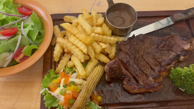 Juicy grilled picanha steak served with crispy fries, fresh salad, vegetables, and sauce on a wooden board