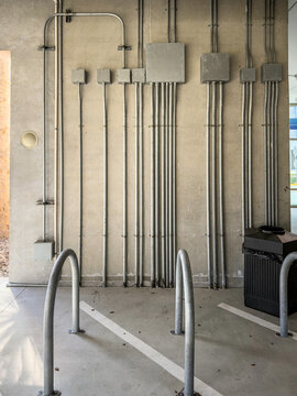 Junction boxes arranged on a wall by U-shaped bollards (impact barriers) along the ground floor of a parking garage by a hospital, for motifs of electrical distribution and safety