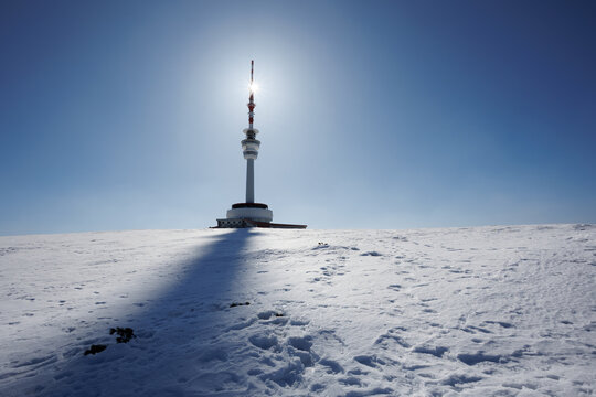 Television and communications tower and transmitter, Praded, Jeseniky mountains, Czech Republic, Czechia. Tall utility building on the top of the mountain and hill. Sun and backlight in the winter.
