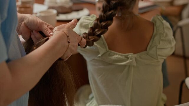 Cropped shot of unrecognizable mother styling daughters hair, doing braid at home