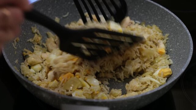 Cooking Kedgeree Mixing Smoked Haddock, Rice, Onion and Boiled Eggs in Frying Pan