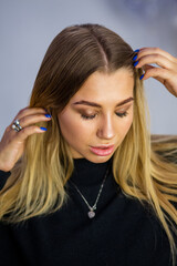 Naklejka premium Young attractive woman adjusting her hair with hands, natural makeup look, beauty portrait in studio environment