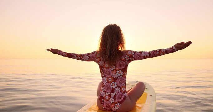 A happy young woman walking on a sup board by the sea during her summer vacation. Slow motion