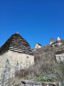 Dargavs City of the Dead necropolis, North Ossetia, Russia. Historic burial site with rows of white crypts stretching across the green landscape
