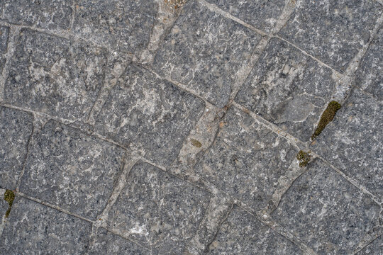 Weathered gray stone pavement texture, irregular cobblestone pattern background, natural rock tile surface, rustic outdoor flooring, cracked stone walkway detail, seamless masonry texture, rough grani