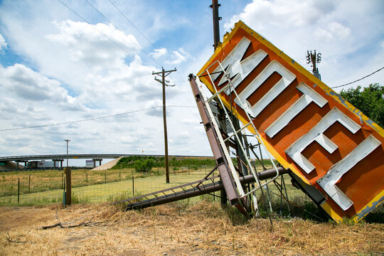 Fallen vintage motel sign in rural landscape, decline of roadside America