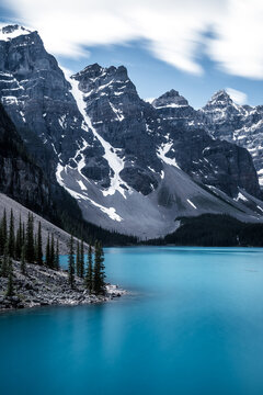 View into land of dramatic sky over mountains and shoreline of Moraine Lake, Banff National Park, Alberta, Canada