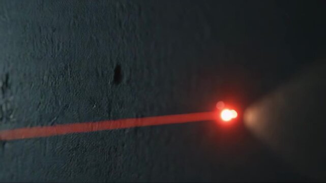 Red laser beam shining on a dark concrete wall  