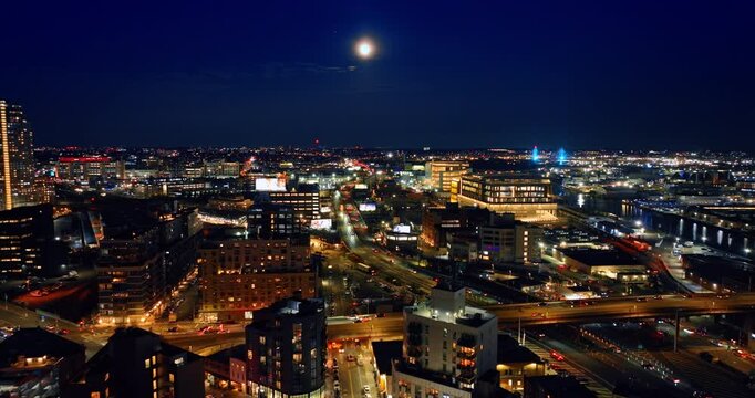 Luminous roads of New York are filled with cars. Night panorama of the city under the full Moon.