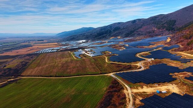 Flight over the natural landscape with sites of solar panels of whimsical shapes. Fields of photovoltaic cells along the mountains.