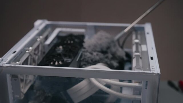 Process maintenance of personal computer, technician using gray duster to remove dust from internal components, ensuring proper airflow and preventing overheating of system, close-up, slow motion.