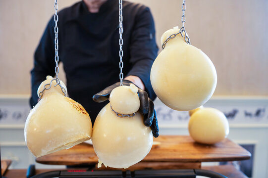Traditional Italian cheese making with hanging caciocavallo cheeses and artisan handling dairy products