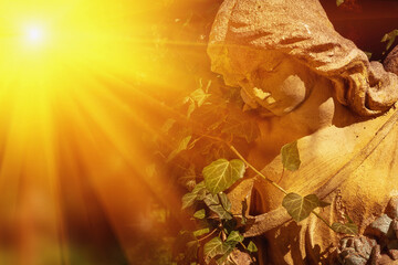 Fototapeta premium Angel statue illuminated by golden sunlight rays, symbolizing hope, divine presence and spiritual peace in warm natural atmosphere.