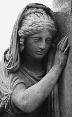 Fototapeta premium Female angel statue leaning on stone, symbolizing grief, tenderness, and quiet emotional farewell in a soft and compassionate composition.