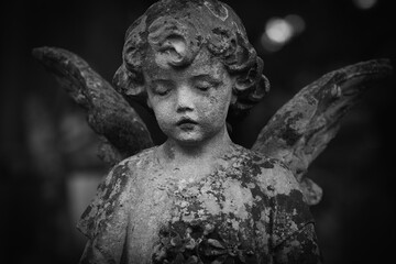 Fototapeta premium Sad child angel statue, symbol of death, mourning and human grief