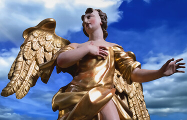 Fototapeta premium Golden angel against blue sky, symbol of hope, protection and divine inspiration