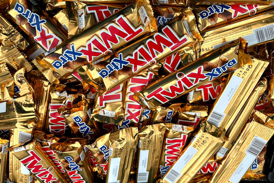 Large pile Twix Xtra chocolate bars gold wrappers, supermarket goods, global food distribution scattered candy, close-up sweet snacks, Sustainable consumerism, textured background commercial branding