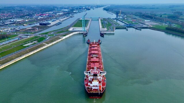 Aerial view of a bulk carrier guided by tugboats entering the new Terneuzen canal lock in the Netherlands