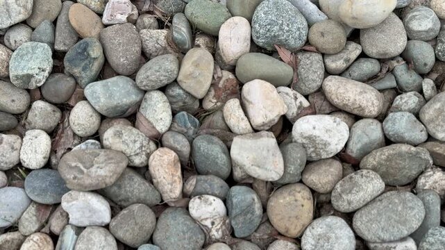 Closeup small stone pebbles on footpath showing neutral gray beige tones, coarse aggregate texture, tight crop, overhead.