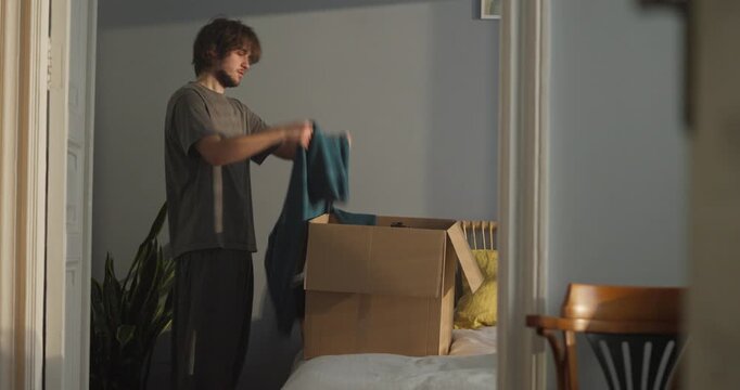 A young person opens a large cardboard box in their room, revealing old clothes and forgotten memories