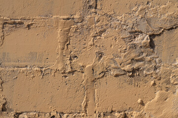 Fototapeta premium Old brick exterior. Aged masonry with chipped plaster and rustic industrial appeal. Worn brick surface featuring rough plaster and timerotted mortar in subdued industrial tones