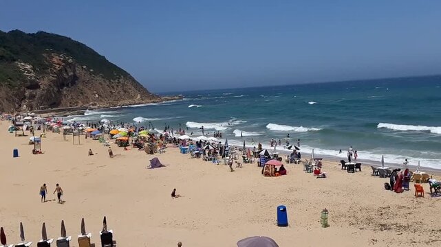 Horizontal 1080p video of Merakala Beach, Tangier, Morocco: sunlit Mediterranean waves, relaxed beachgoers, and vibrant coastal lifestyle&mdash;perfect for travel, tourism, and global campaigns.