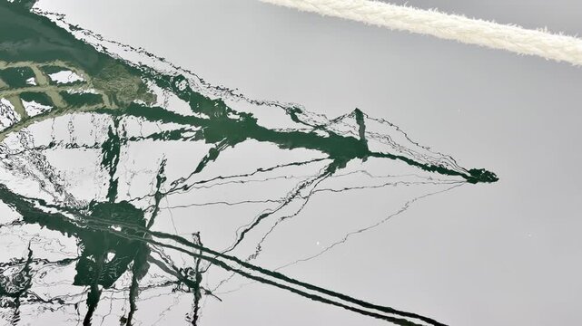Water reflection of the mast and rigging of Etoile du Roy in Saint Malo harbor, Brittany, France, revealing historic sailing details and a classic maritime atmosphere