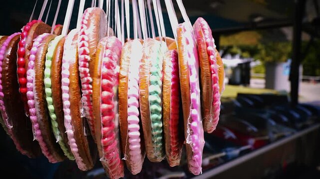 Drehende Lebkuchenherzen mit sichtbarem Schriftzug aus Zuckerglasur auf einem sonnigen Volksfest oder Oktoberfest, traditionelle S&uuml;&szlig;igkeit in Nahaufnahme