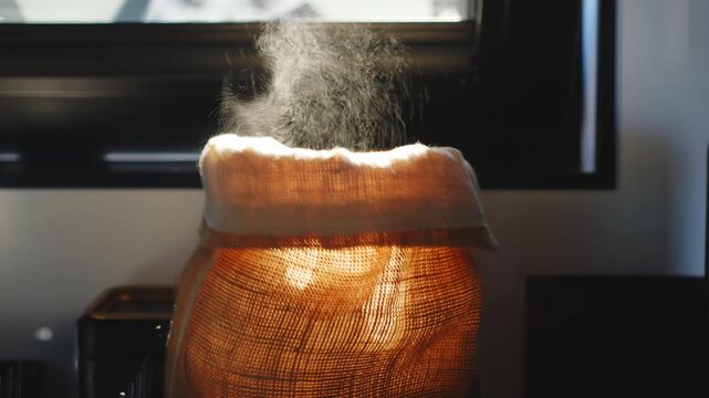 Close up of a person reaching into a textile bag to take out a loaf of bread in a bright morning kitchen