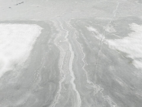 Aerial View of Frozen Lake Ice With Snow Patches in British Columbia, Canada Winter Landscape