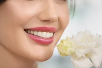Fototapete Schönheitssalon Close-up of beautiful woman's lips with white flowers on background. Model beauty face with nice smile. Spring seasonal beauty concept. Selective focus.  © jutaphoto