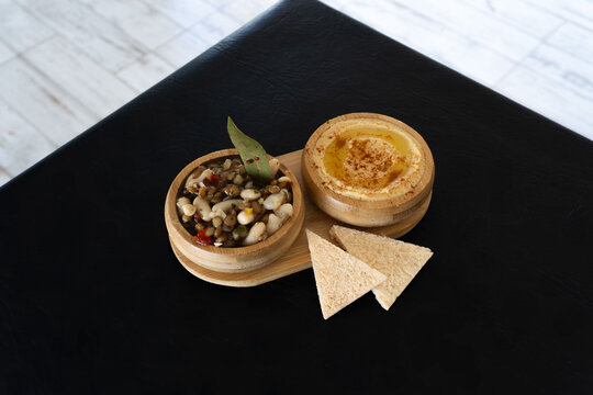Primer plano de hummus fresco con piment&oacute;n y pan de pita. Vista detallada de aperitivos tradicionales de Oriente Medio. Enfoque en la textura cremosa del hummus y los ingredientes frescos de la ensala