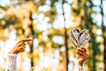 Woman hands holding wooden heart in forest expressing love for nature and environment. Close up detail with trees in background, outdoor lifestyle and sustainability concept during peaceful leisure ti