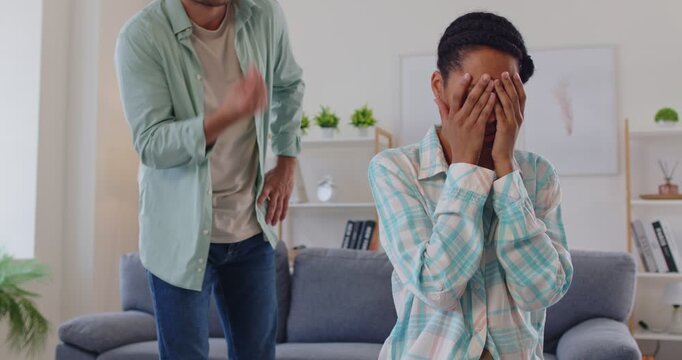 Conflict of unhappy couple at home, upset frustrated woman in argument with boyfriend in living room. Sad girl silent, covering face with hands in boredom, angry man talking. Breakup, divorce problem